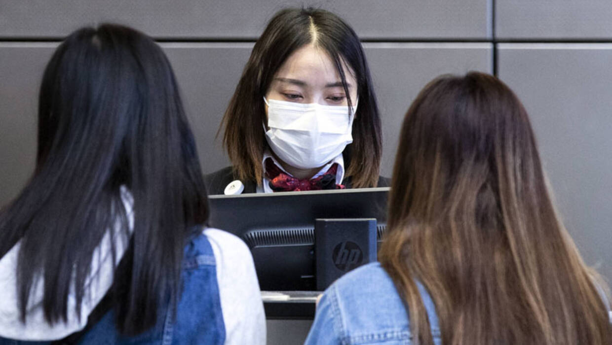 Pracownicy China Airlines w maskach na twarz dokonują odprawy pasażerów w Tajpej na lotnisku LAX Tom Bradley International Airport w Los Angeles, Kalifornia, USA. Fot. PAP/EPA / ETIENNE LAURENT 
