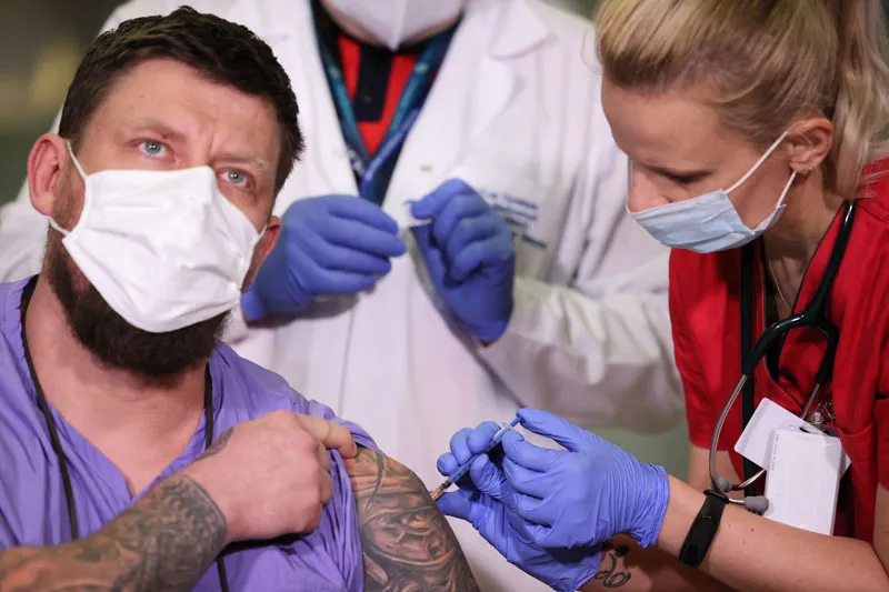 Ratownik medyczny Sławomir Butkiewicz (C), lekarz chorób zakaźnych Agnieszka Szarowska (P) i zastępca dyrektora ds. medycznych dr n. med. Artur Zaczyński (L) podczas szczepienia przeciw koronawirusowi Covid-19 na terenie Centralnego Szpitala Klinicznego MSWiA w Warszawie. Fot. PAP/Leszek Szymański