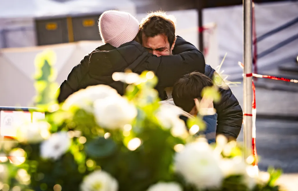 Ludzie pocieszają się nawzajem w pobliżu baru, gdzie wybuchł pożar w wyniku eksplozji Fot. PAP/EPA/JEAN-CHRISTOPHE BOTT