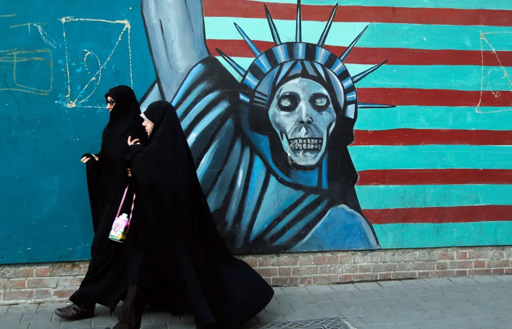 Zdjęcie archiwalne z 3 listopada 2016 r. przedstawia Iranki przechodzące obok antyamerykańskiego muralu w drodze do byłej ambasady USA w Teheranie Fot. PAP/EPA/ABEDIN TAHERKENAREH