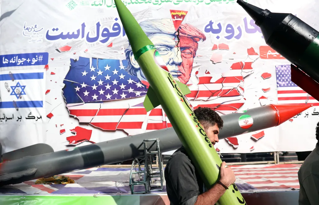 Іранський чоловік несе макет ракети, проходячи повз карикатуру, що зображує президента США Дональда Трампа, Тегеран, Іран, 4 листопада 2025 року. Фотоілюстрація. Fot. PAP/EPA/ABEDIN TAHERKENAREH