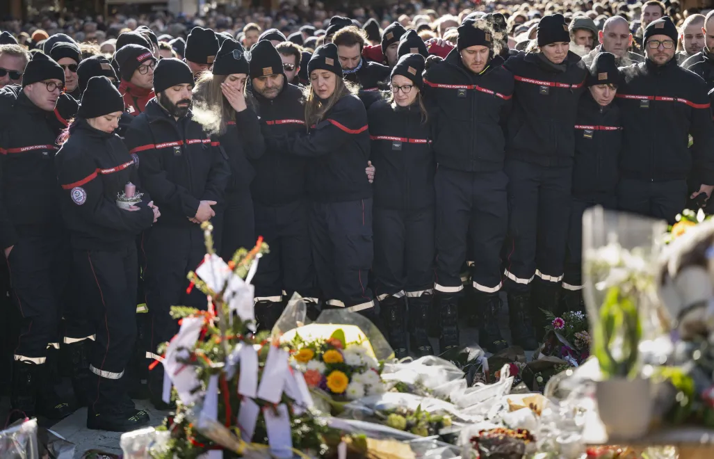 Strażacy z Crans-Montana zgromadzili się wokół kwiatów i zniczy, aby uczcić pamięć ofiar Fot. PAP/EPA/JEAN-CHRISTOPHE BOTT