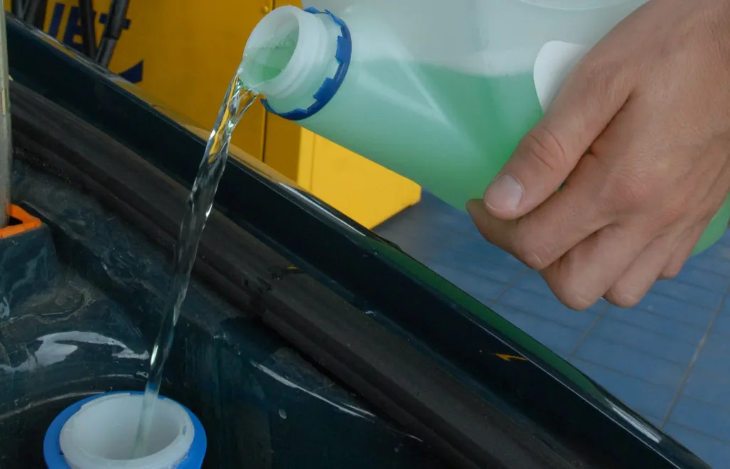 Kierowca uzupełnia płyn do spryskiwaczy w samochodzie Fot. PAP/Barbara Ostrowska