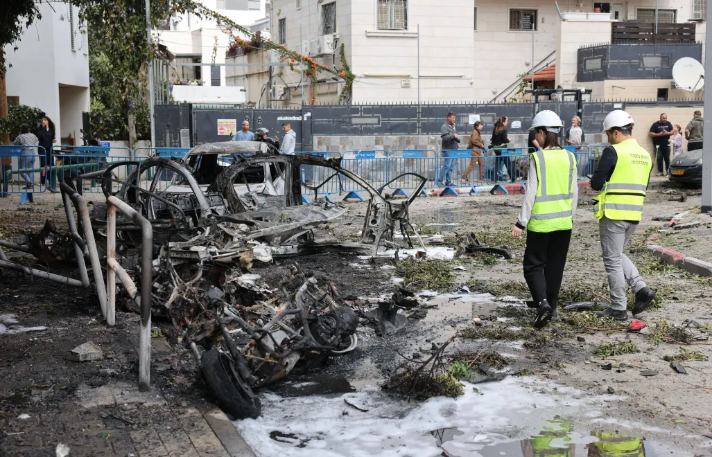 Израильские спасатели осматривают сгоревшие автомобили после попадания осколков от перехваченной иранской баллистической ракеты в Тель-Авиве. Fot. PAP/EPA/ABIR SULTAN