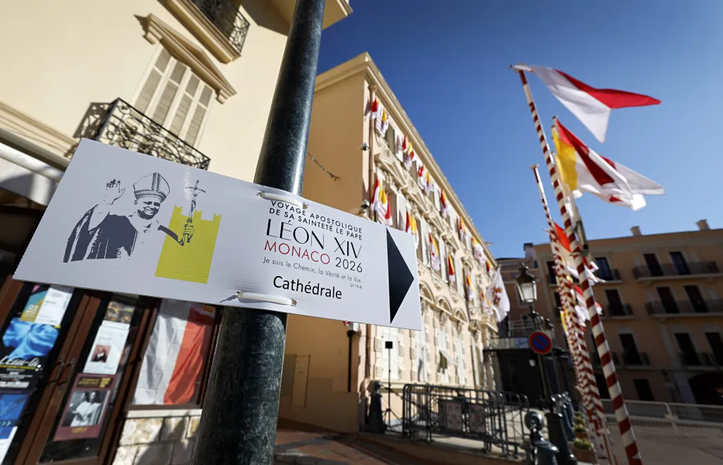 Flagi Watykanu i tablice informacyjne na ulicach Monako, fot. PAP/EPA/SEBASTIEN NOGIER