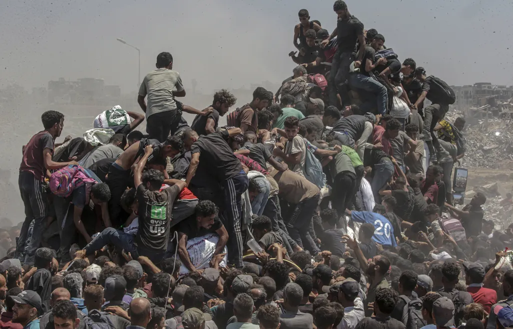 Palestyńczycy ze Strefy Gazy wspinających się na ciężarówkę z pomocą humanitarną, fot. PAP/EPA/MOHAMMED SABER