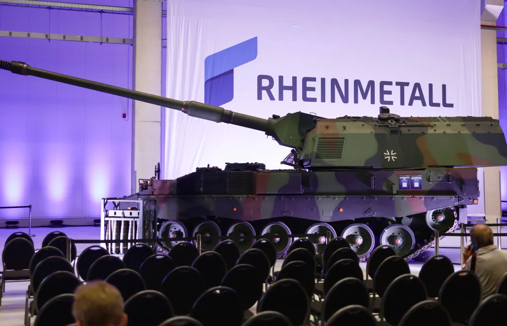 Логотип компанії Rheinmetall на тлі танка Howitzer 2000. Фотоілюстрація. Fot. PAP/EPA/HANNIBAL HANSCHKE