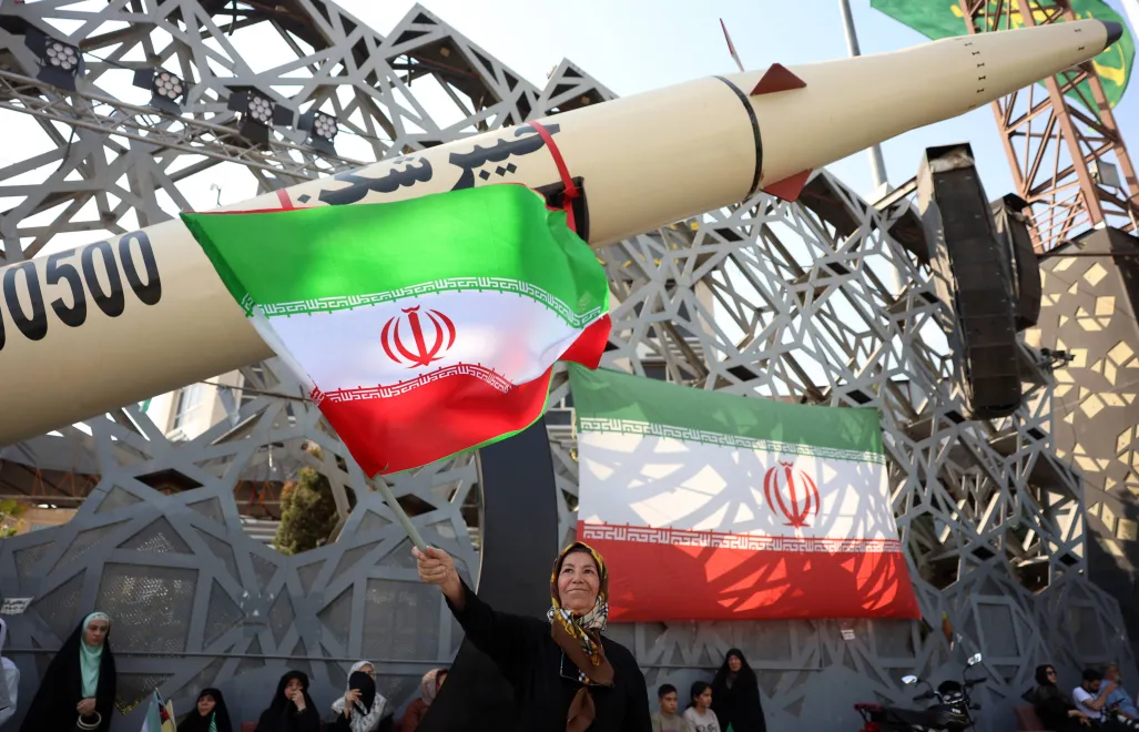 Iranka z flagą podczas wiecu na tle rakiety balistycznej Fot. PAP/EPA/ABEDIN TAHERKENAREH