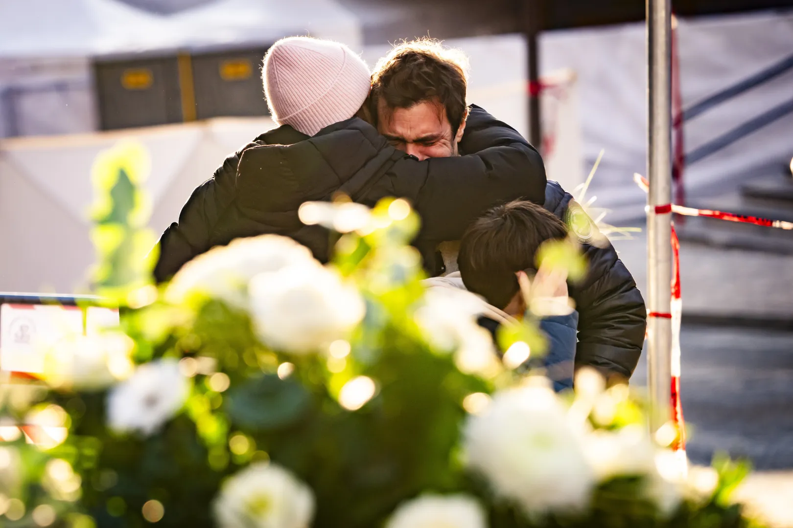 Ludzie pocieszają się nawzajem w pobliżu baru, gdzie wybuchł pożar w wyniku eksplozji Fot. PAP/EPA/JEAN-CHRISTOPHE BOTT