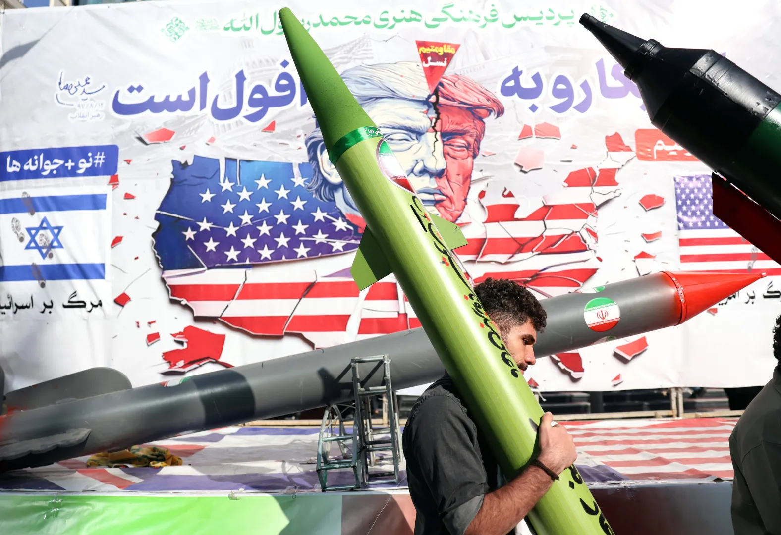 Іранський чоловік несе макет ракети, проходячи повз карикатуру, що зображує президента США Дональда Трампа, Тегеран, Іран, 4 листопада 2025 року. Фотоілюстрація. Fot. PAP/EPA/ABEDIN TAHERKENAREH