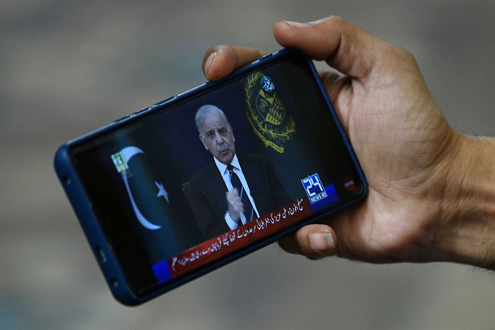 Telefon z wyświetlonym przemówieniem premiera Pakistanu Shehbaza Sharifa. Fot PAP/EPA/SHAHZAIB AKBER 