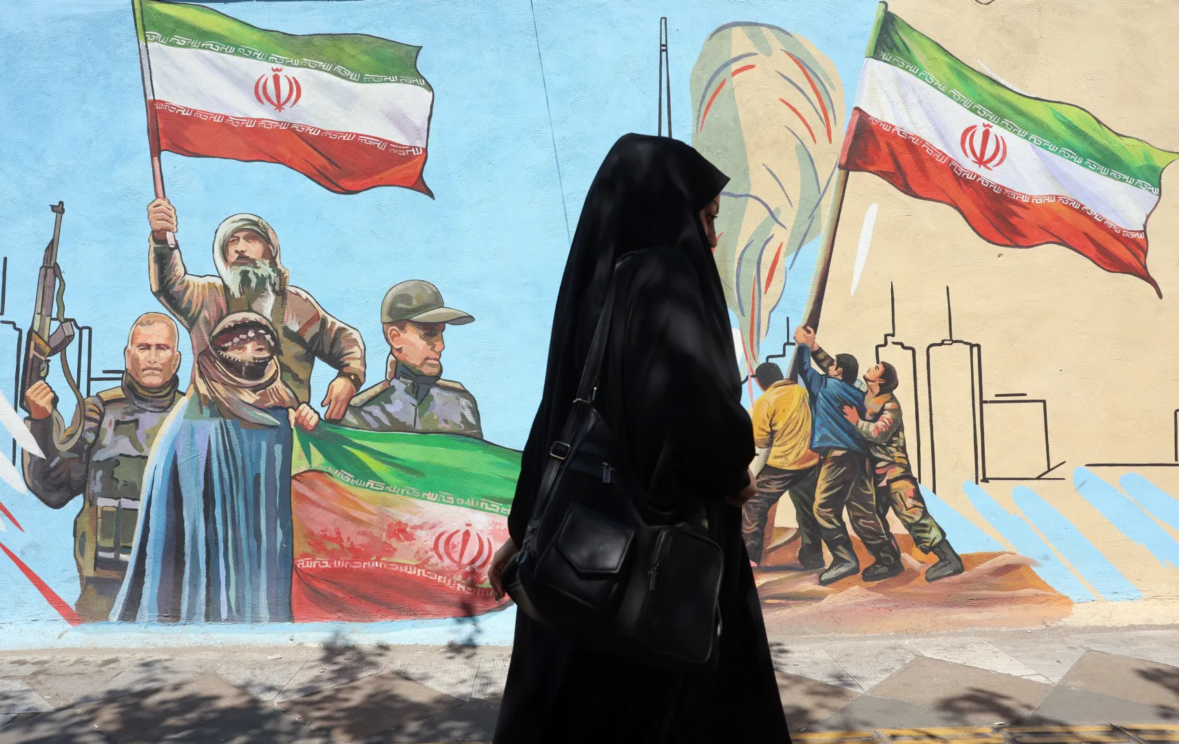 Zamaskowana Iranka przechodzi obok muralu na ulicy w Teheranie Fot. PAP/EPA/ABEDIN TAHERKENAREH
