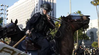 Policjant na koniu uderza w transparent podczas protestu w Los Angeles Fot. PAP/EPA/CAROLINE BREHMAN