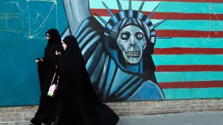 Zdjęcie archiwalne z 3 listopada 2016 r. przedstawia Iranki przechodzące obok antyamerykańskiego muralu w drodze do byłej ambasady USA w Teheranie Fot. PAP/EPA/ABEDIN TAHERKENAREH