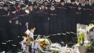 Strażacy z Crans-Montana zgromadzili się wokół kwiatów i zniczy, aby uczcić pamięć ofiar Fot. PAP/EPA/JEAN-CHRISTOPHE BOTT