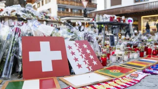 Kwiaty i znicze w hołdzie ofiarom przed barem w Crans-Montanie, fot. PAP/EPA/KEYSTONE/CYRIL ZINGARO