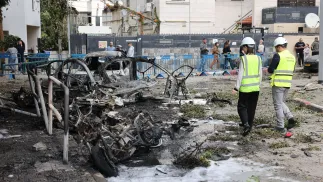 Израильские спасатели осматривают сгоревшие автомобили после попадания осколков от перехваченной иранской баллистической ракеты в Тель-Авиве. Fot. PAP/EPA/ABIR SULTAN