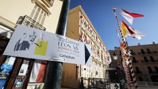 Flagi Watykanu i tablice informacyjne na ulicach Monako, fot. PAP/EPA/SEBASTIEN NOGIER