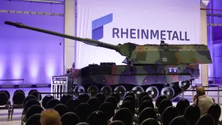 Логотип компанії Rheinmetall на тлі танка Howitzer 2000. Фотоілюстрація. Fot. PAP/EPA/HANNIBAL HANSCHKE