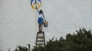 Graffiti autorstwa włoskiego artysty TV Boya na murze budynku w Buczy. Fot. PAP/	Vladyslav Musiienko