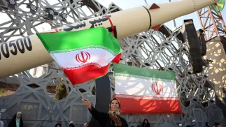 Iranka z flagą podczas wiecu na tle rakiety balistycznej Fot. PAP/EPA/ABEDIN TAHERKENAREH