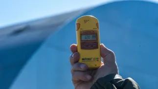 Dozymetr do pomiaru promieniowania na tle kopuły nad zniszczonym reaktorem elektrowni jądrowej w Czarnobylu. Fot. PAP/Vladyslav Musiienko