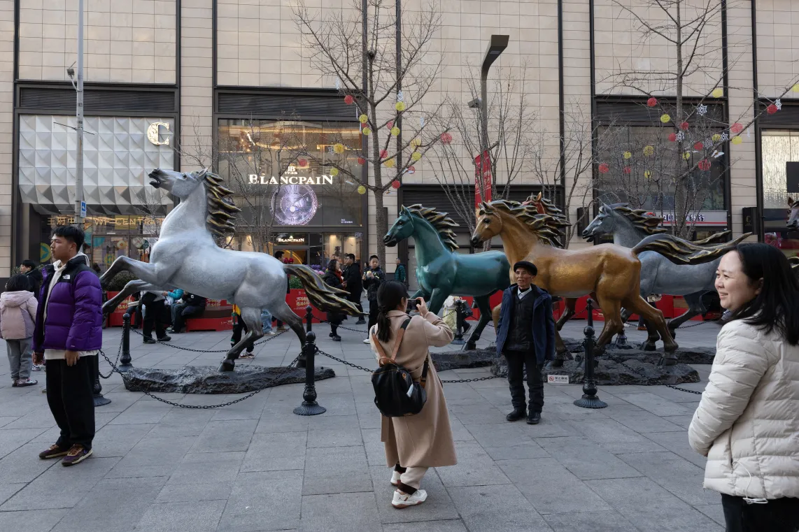 Ludzie pozują przed instalacją koni w centrum handlowym przed Chińskim Nowym Rokiem w Pekinie. Fot.  EPA/JESSICA LEE 