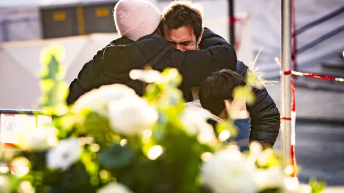 Ludzie pocieszają się nawzajem w pobliżu baru, gdzie wybuchł pożar w wyniku eksplozji Fot. PAP/EPA/JEAN-CHRISTOPHE BOTT