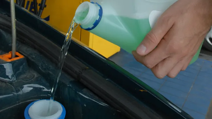 Kierowca uzupełnia płyn do spryskiwaczy w samochodzie Fot. PAP/Barbara Ostrowska