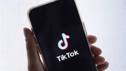Osoba trzyma telefon komórkowy z logo TikTok. Fot. PAP/ EPA/ Caroline Brehman