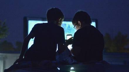 Dzieci siedzące przed telewizorem i używające smartfona. Zdj. ilustracyjne. Fot. PAP/Marcin Obara