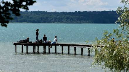 Ludzie cieszą się słonecznym dniem na drewnianej kładce nad jeziorem. Fot. EPA/RONALD WITTEK