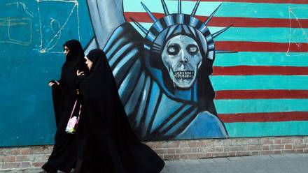 Zdjęcie archiwalne z 3 listopada 2016 r. przedstawia Iranki przechodzące obok antyamerykańskiego muralu w drodze do byłej ambasady USA w Teheranie Fot. PAP/EPA/ABEDIN TAHERKENAREH