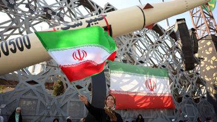 Iranka z flagą podczas wiecu na tle rakiety balistycznej Fot. PAP/EPA/ABEDIN TAHERKENAREH